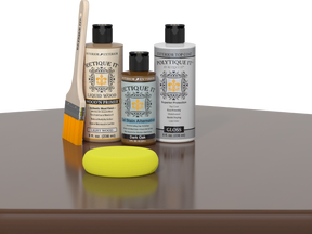Retique It® Light Wood Wood’n Primer with Dark Oak Gel Stain Alternative, gloss topcoat, brush, and yellow sponge on a reflective tabletop.