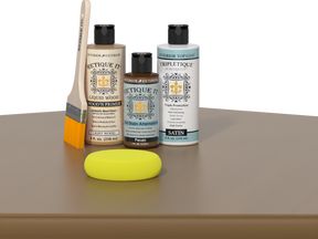 Retique It® Pecan Multipurpose Kit contents with Light Wood Liquid Wood primer, Pecan gel stain alternative, Tripletique satin interior top coat, paintbrush, and yellow sponge displayed on a wood surface.