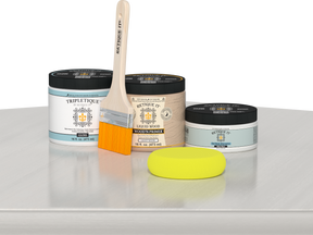 Retique It® White Wash Multipurpose Kit contents with Liquid Wood primer, White Wash gel stain alternative, Tripletique gloss interior top coat, paintbrush, and yellow sponge displayed on a white wood surface.
