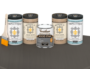 64 oz Retique It Liquid Wood kit with Weathered Gray stain, matte Tripletique topcoat, and a paintbrush on a matching finished tabletop.
