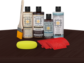 Retique It® Wood'n Finish Kit in Red Mahogany stain displayed on a table, showcasing wood finishing products and application tools.